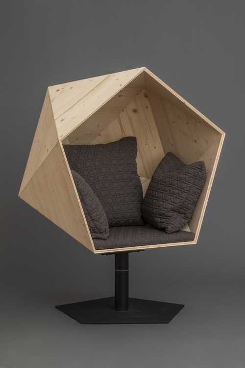 Soft chair enclosed in a geometric shell on pedestal